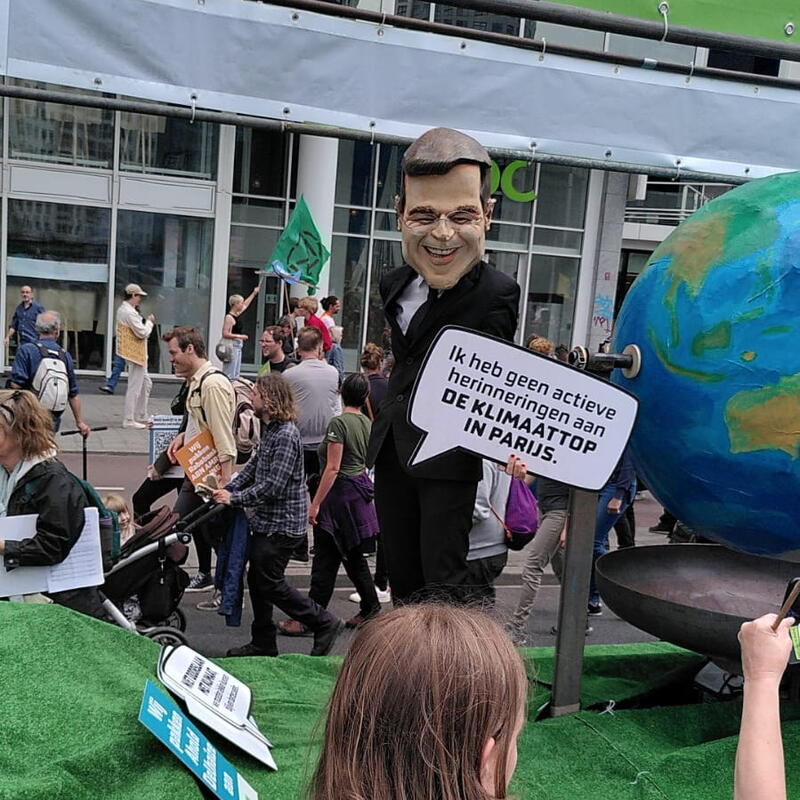 Iemand verkleed als een Mark Rutte karikatuur, op een wagen van Milieudefensie tijdens de Klimaatmars in Rotterdam.